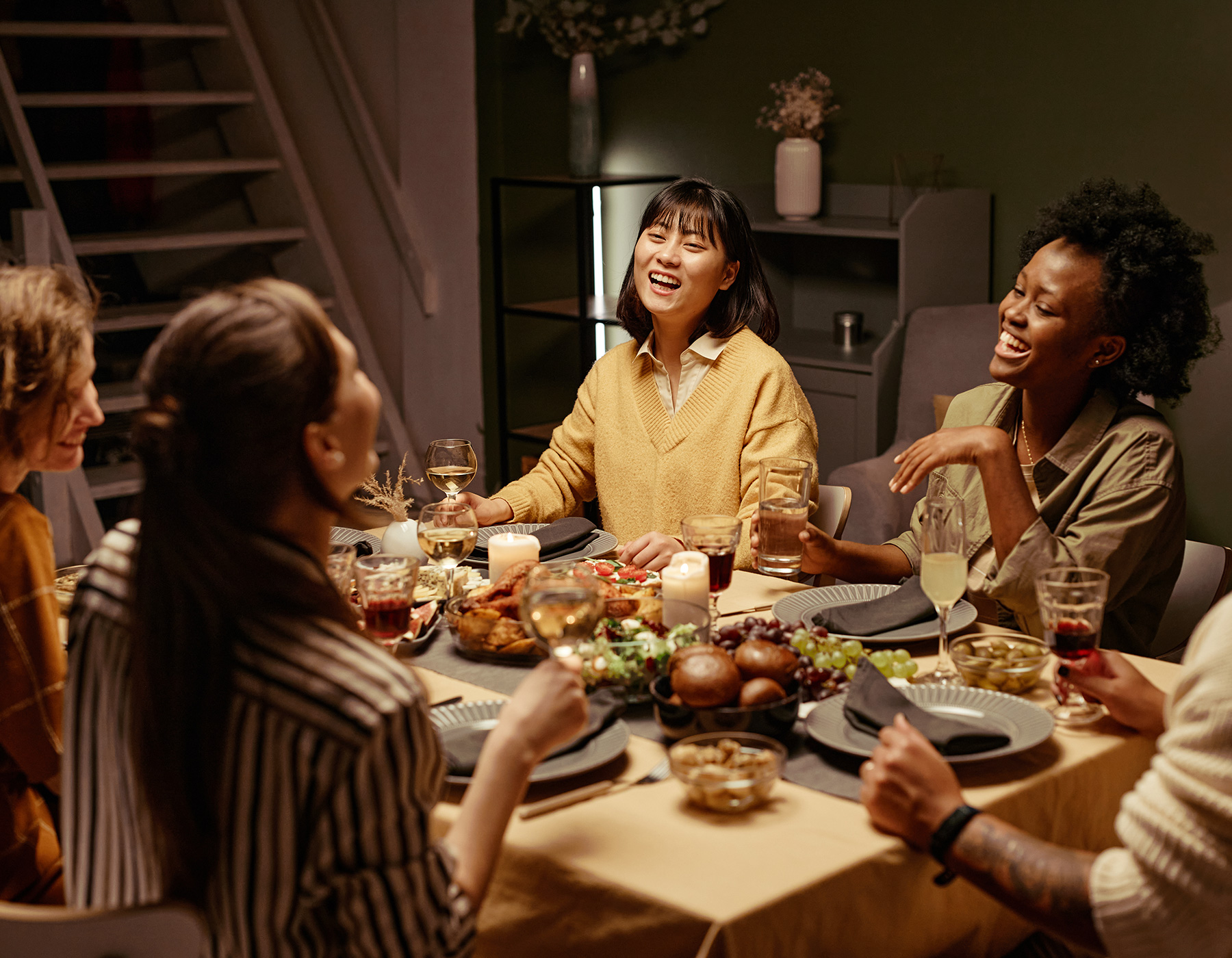 Freunde sitzen zum Essen am Tisch in einem gemütlichen Ambiente und haben Spaß