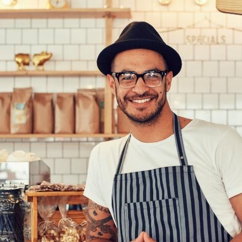 Barista aus der Gastronomie steht im meinCafé und erwartet Gäste, die er bedienen kann