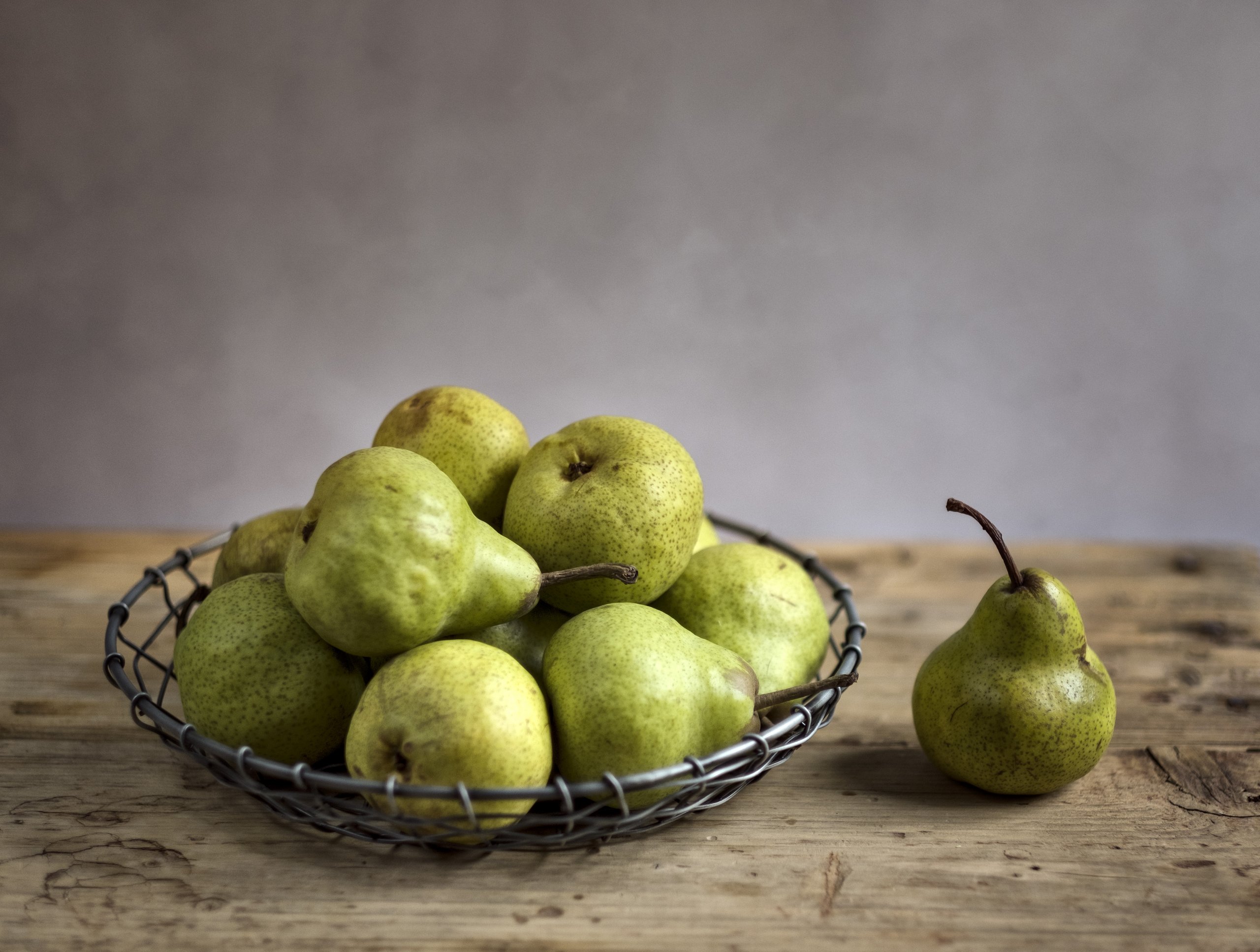 Gesunde und frische Birnen in einem Obstkorb auf einem Holztisch