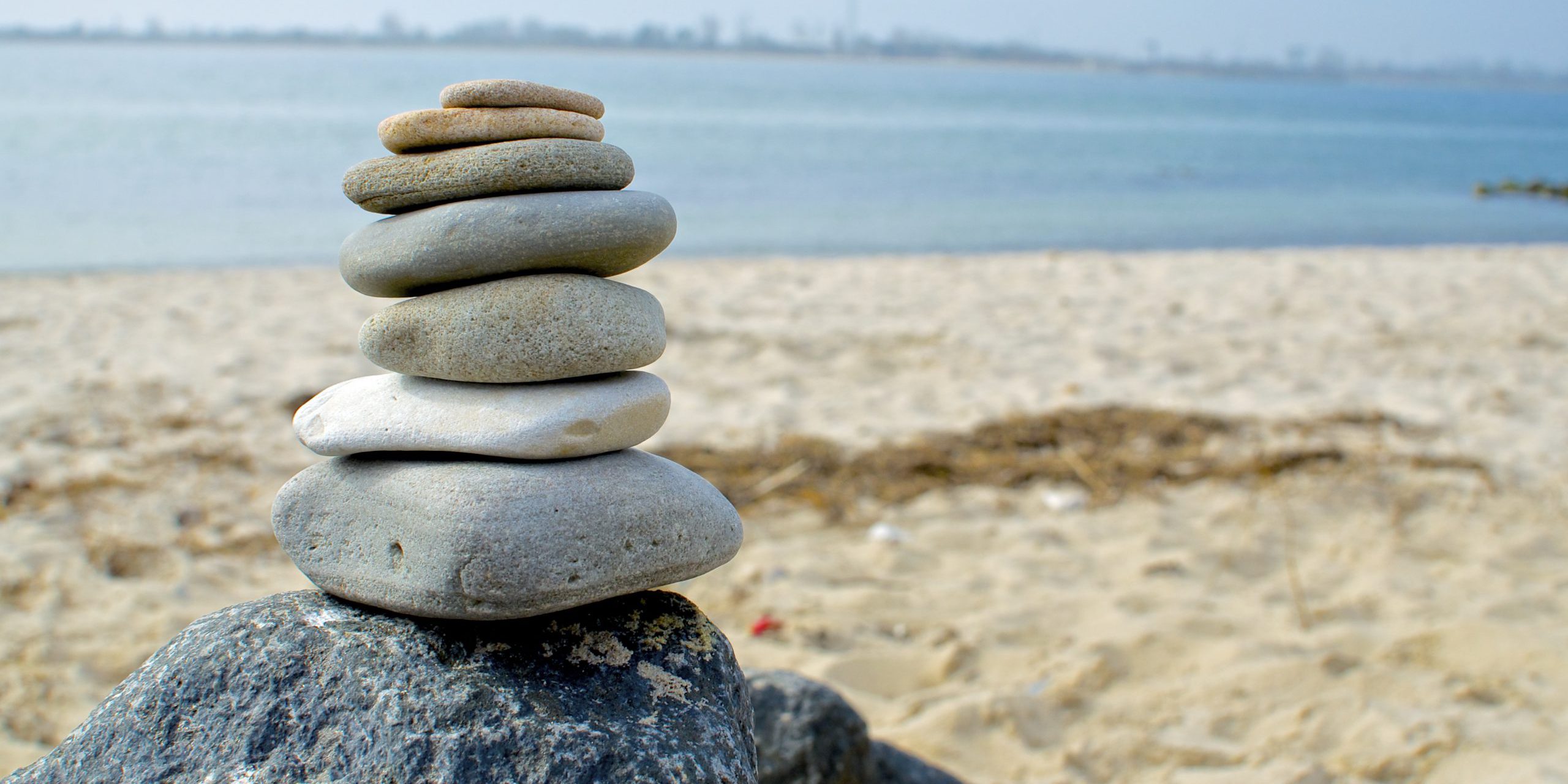 Gestapelte Steine am Strand symbolisieren Balance in der Unternehmenskultur