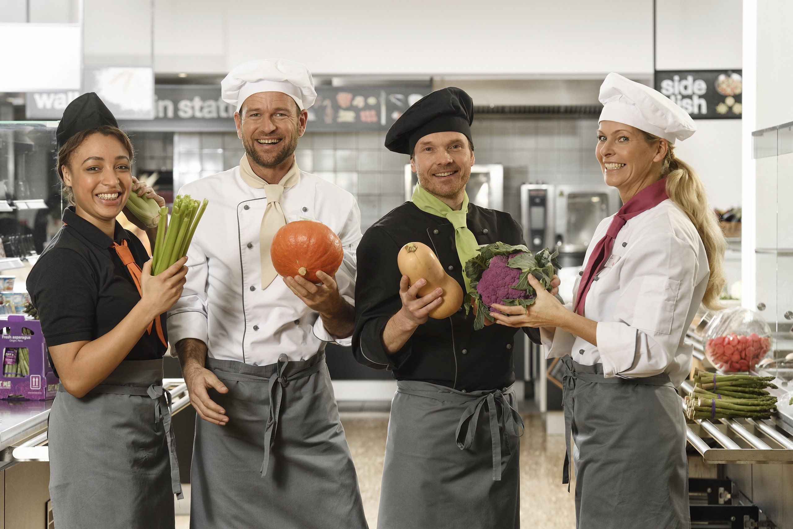 Küchenteam von apetito catering mit frischem Gemüse freut sich auf die Verpflegung der Gäste und Mitarbeiter 