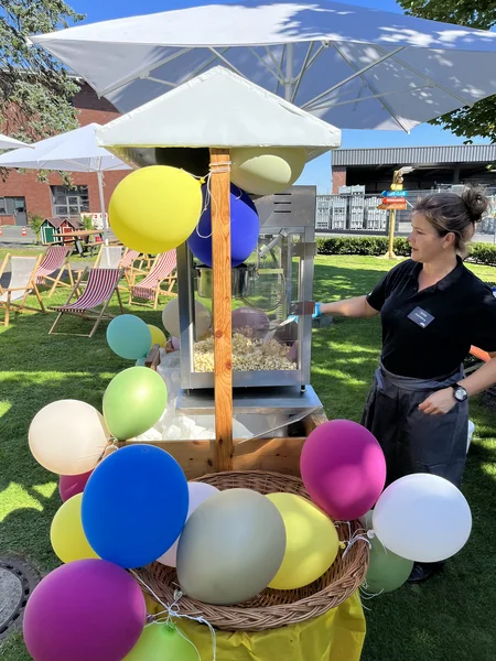 Popcornstand mit bunten Luftballons auf grünem Rasen bei der Jubiläumsfeier der Westfalen AG