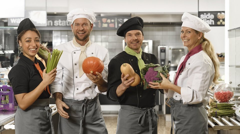 Küchenteam von apetito catering mit frischem Gemüse freut sich auf die Verpflegung der Gäste und Mitarbeiter 