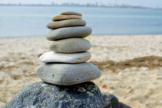 Gestapelte Steine am Strand symbolisieren Balance in der Unternehmenskultur