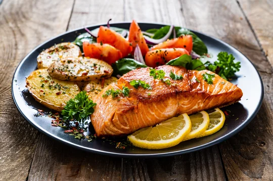 Gesunder Lachs mit frischem Gemüse, Rosmarinkartoffeln und Zitronen lecker serviert