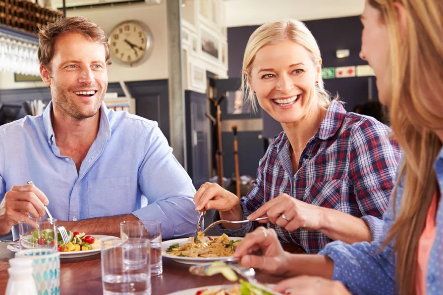 Mitarbeiter genießen das Mittagessen mit Pasta und einem frischen Salat im Betriebsrestaurant